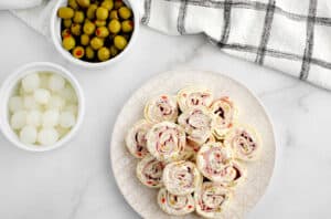 Green Olive and Ham Rollups on Plate with Green Olive and Cocktail Onions in Bowls
