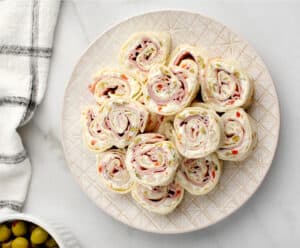 Green Olive and Ham Rollups on Plate with Kitchen Towel on Side