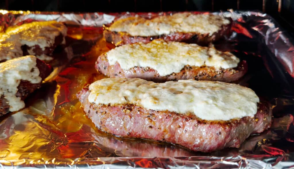 Steaks Topped with Gorgonzola Butter Broiling in the Oven