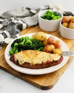 Steak Topped with Gorgonzola Plated with Broccoli and Potatoes on Wooden Surface
