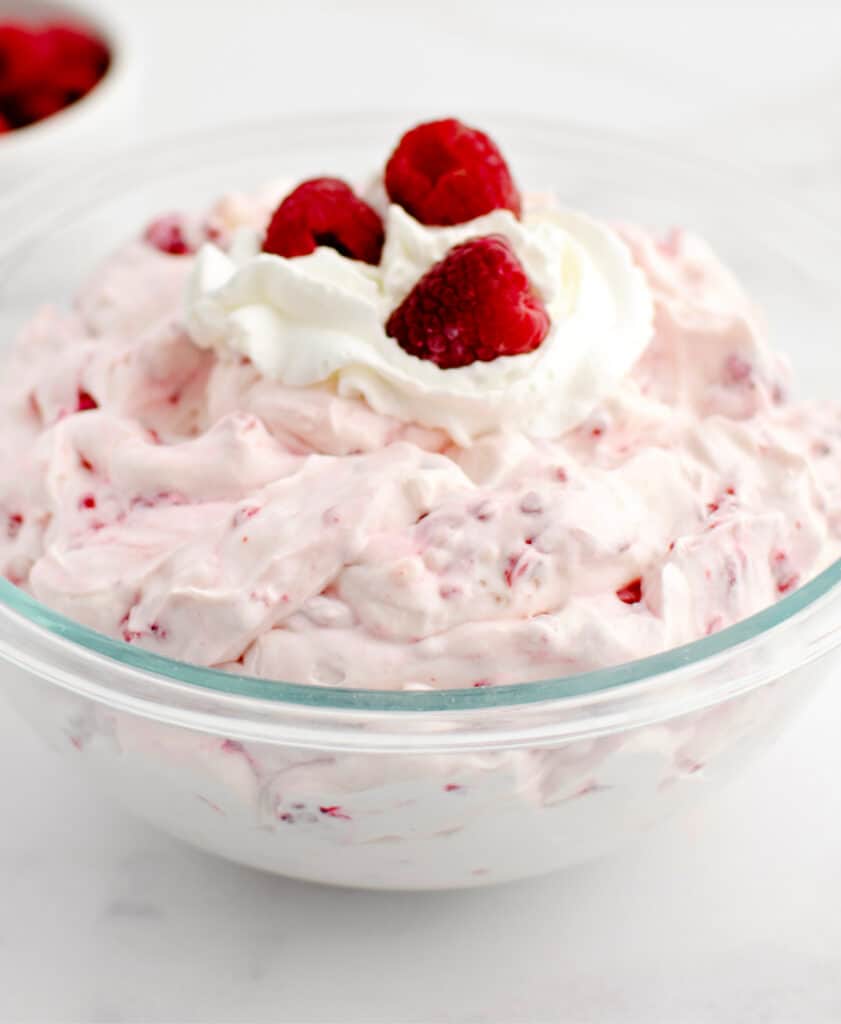 Raspberry Cheesecake Salad in Serving Bowl with Whipped Topping and Fresh Raspberries on Top