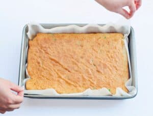 Removing boxed cake with parchment paper from 9 by 13 pan