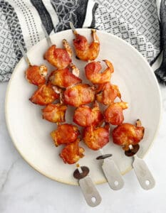 Bacon Wrapped Shrimp Skewers on Plate with Kitchen Towel in the Background