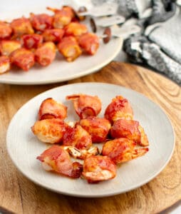 Bacon Wrapped Shrimp on Plate with Kabobs in the Background