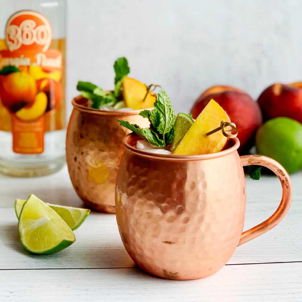 Peach Moscow Mules in Copper Mugs Closeup with Garnish and Lime