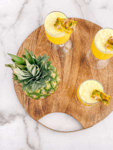 Pineapple mimosas with pineapple chunk garnishes on a tray overhead view