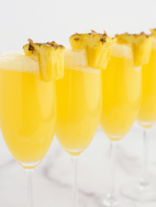 Pineapple mimosas in a line with pineapple garnishes