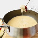 Dipping a red apple in cheddar cheese fondue