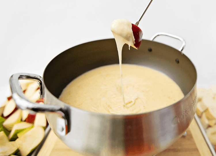 Dipping a red apple in cheddar cheese fondue