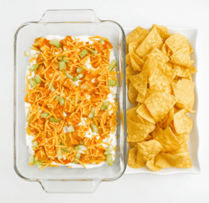 Buffalo Chicken Dip in Glass Baking Dish with White Platter of Tortilla Chips