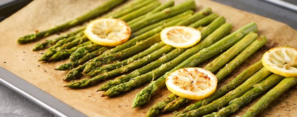 Cooked Asparagus Topped with Lemon Slices on a Baking Sheet with Parchment Paper - Side Dish for Meatloaf