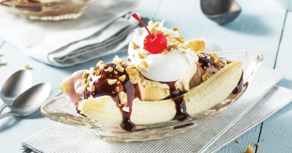 Banana Split in a Dish with Ice Cream, Bananas, Chocolate Sauce, Whipped Cream, Chopped Nuts, and Maraschino Cherry