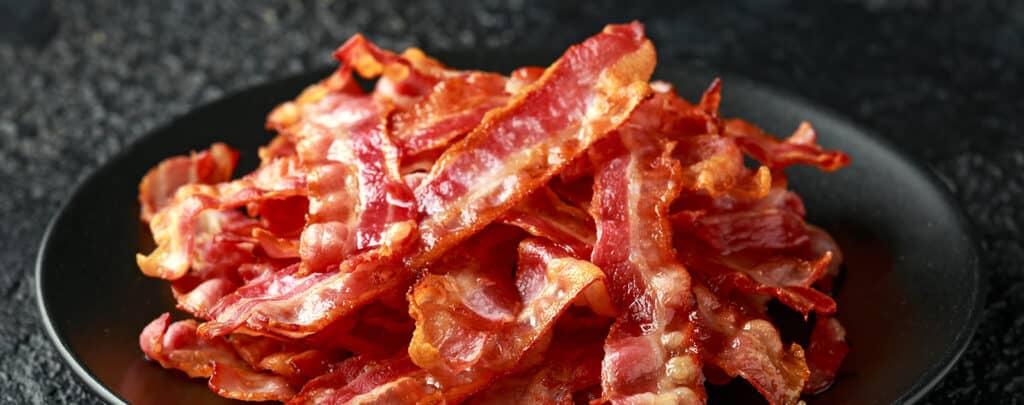 Bacon Piled High on a Black Plate and Dark Countertop