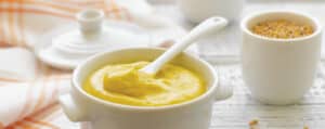 Mustard in a White Bowl with a Serving Spoon