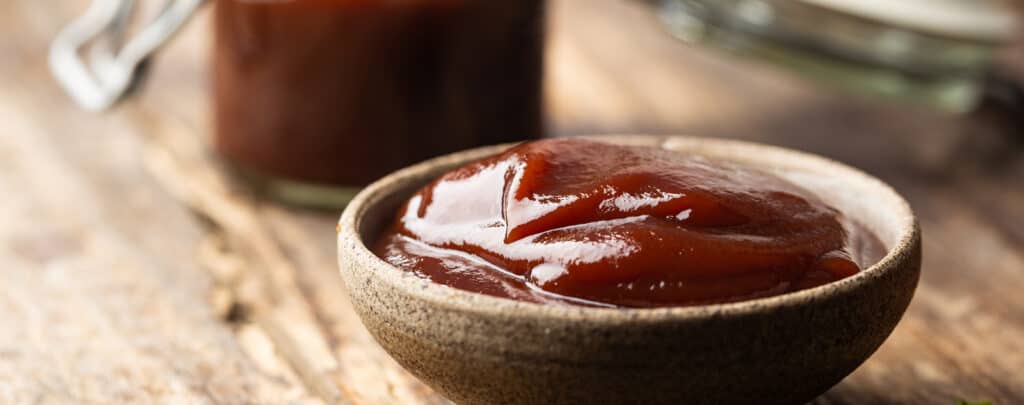 Barbecue Sauce in a Wooden Bowl on a Wooden Surface