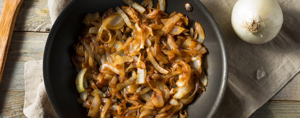 Caramelized Onions in a Skillet with Fresh Onion on the Side