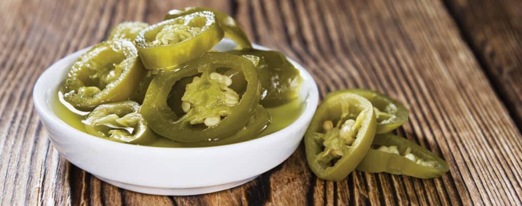 Chopped Jalapenos in a White Bowl on a Wooden Table