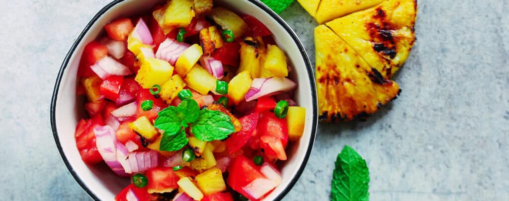 Fresh Salsa with Corn, Tomatoes, Onion, and Fresh Herbs on a Grey Surface