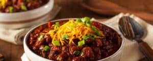 Bowl of Chili with Cheese and Green Onions and Spoon