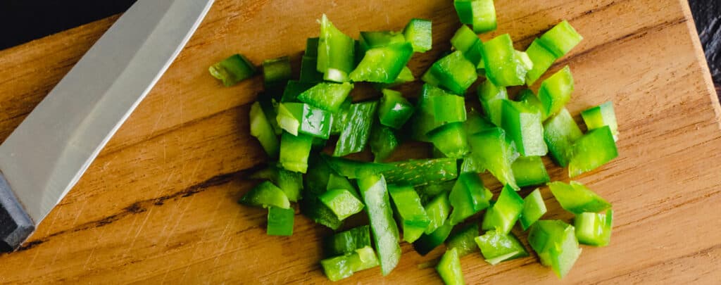 Diced Green Peppers on a Wooden Cutting Board with a Knife
