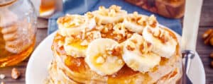 Pancakes Topped with Chopped Nuts, Banana Slices, and Syrup