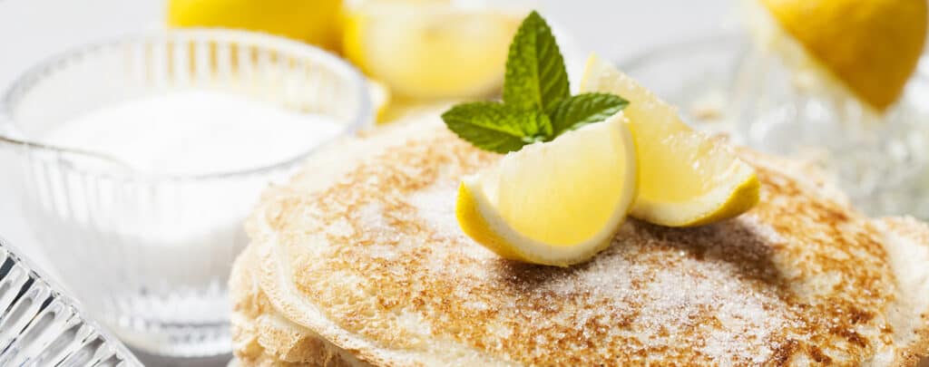 Pancakes Topped with Lemon Juice, Sugar, and Garnished with Lemon Wedges