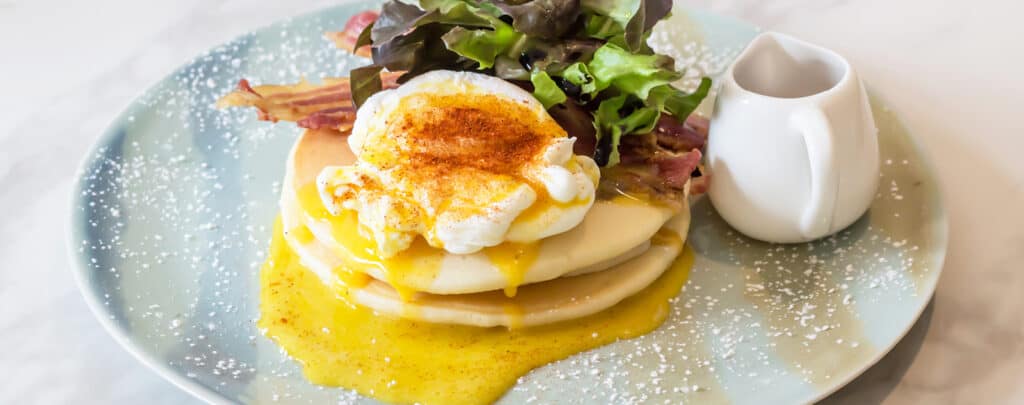 Pancakes Topped with Eggs Benedict and Fresh Greens