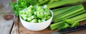 Chopped Celery in a White Bowl with Celery Sticks