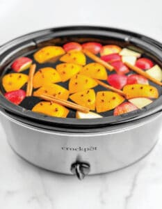 Apple Cider in Slow Cooker with Oranges, Apples, Cloves, and Cinnamon Sticks