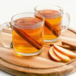 Hot Apple Cider in Glass Mugs with Cinnamon Sticks and Apple Slices