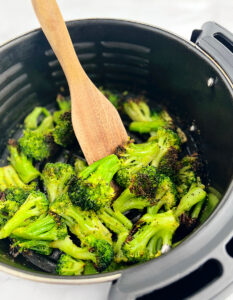 Roasted Frozen Broccoli in Air Fryer Basket with Wooden Spoon