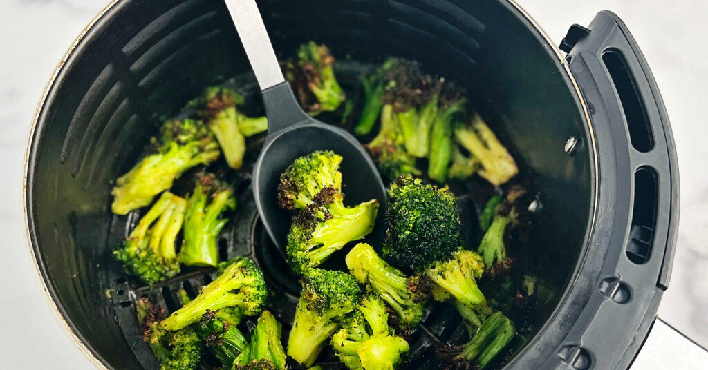 Frozen Broccoli Cooked in Air Fryer Basket with Spoon