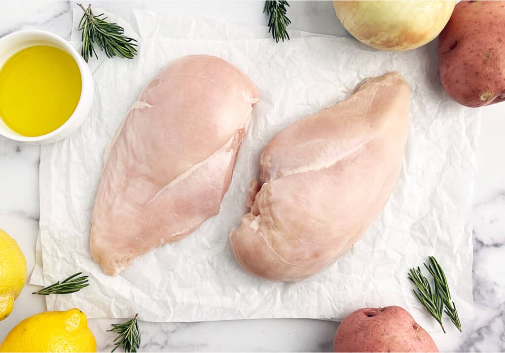 Raw Chicken on Parchment with Olive Oil, Lemon, Potatoes, and Rosemary