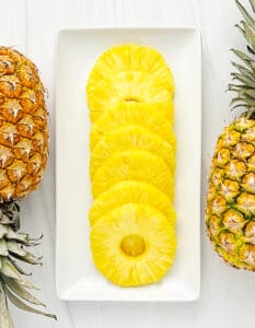 Pineapple Rings on a White Serving Tray with Whole Pineapples on Each Side