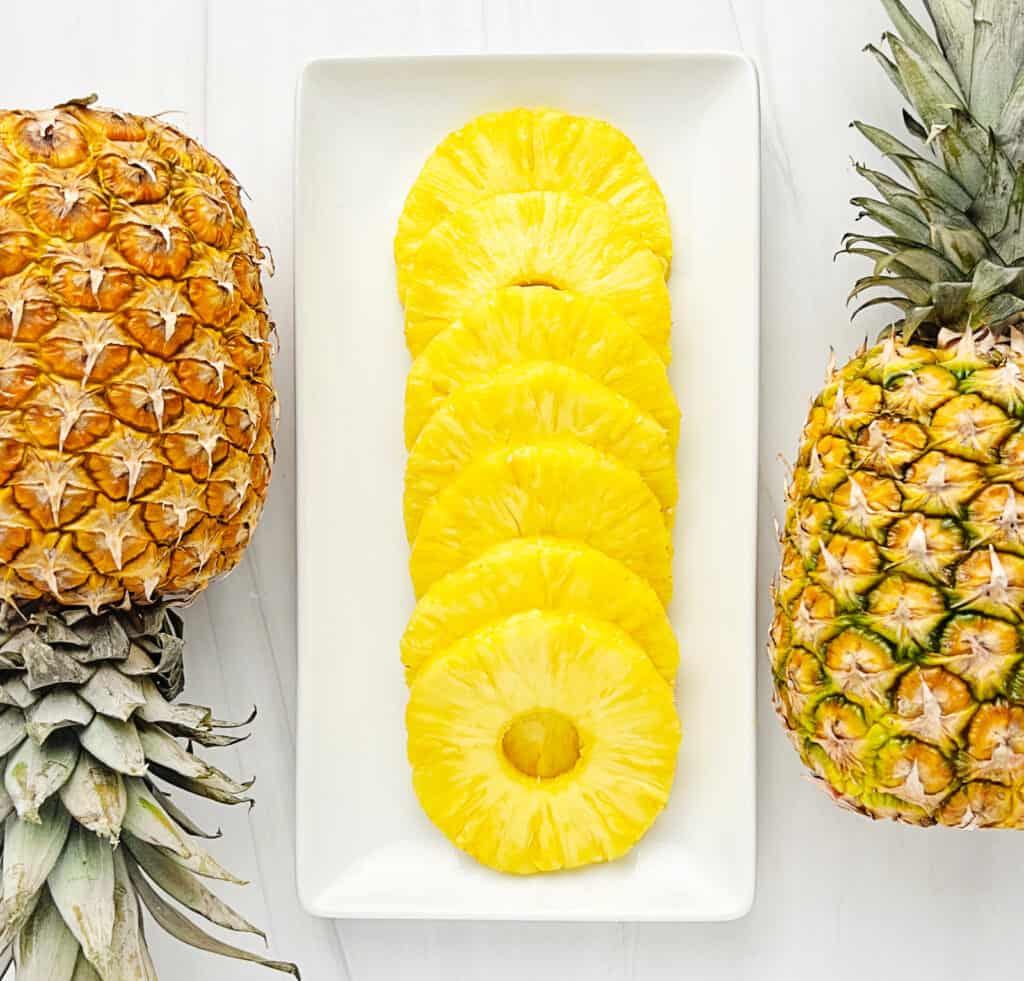 Pineapple Rings on a White Serving Tray with Whole Pineapples on Each Side