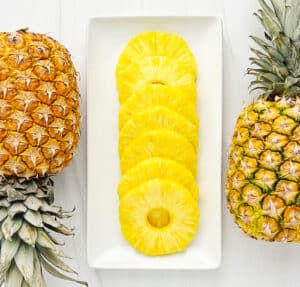Pineapple Rings on a White Serving Tray with Whole Pineapples on Each Side