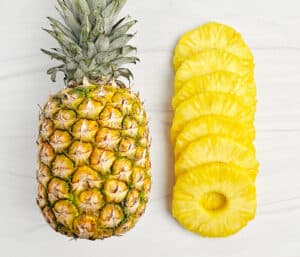 Whole Pineapple Next to Hand Cut Pineapple Slices