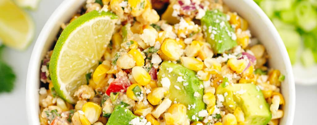 Mexican Street Corn Salad in Bowl with Limes and Avocado