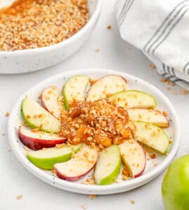 Caramel Apple Dip in the Center of a White Plate with Apples Fanned Around