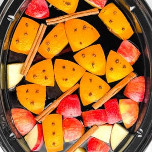 Apple Cider in Slow Cooker with Oranges, Apples, Cinnamon Sticks, and Cloves