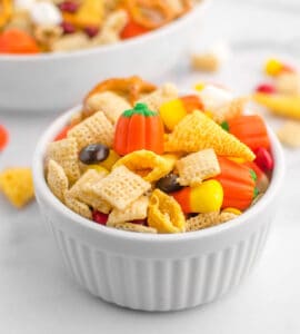 Fall Treat Mix in Small White Serving Bowls with Larger Bowl of Snack Mix in the Background