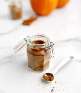 Pumpkin Spice in Spice Jar with Spoon of Spice on White Marble Surface