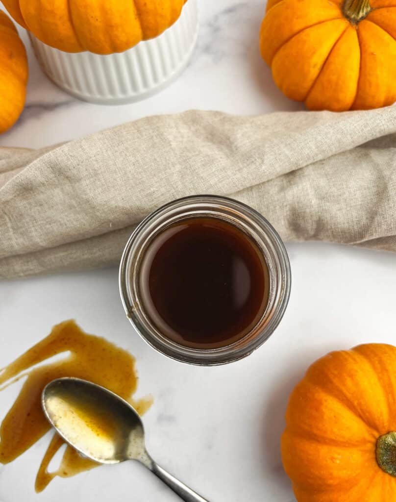 Pumpkin Spice Syrup in Jar with Towel and Pumpkins Surrounding