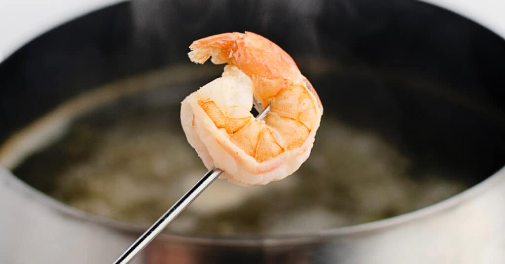 Shrimp on Fondue Stick with Fondue Pot in the Background