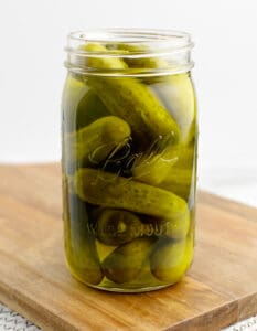 Dill Pickles in a Jar on a Wooden Cutting Board