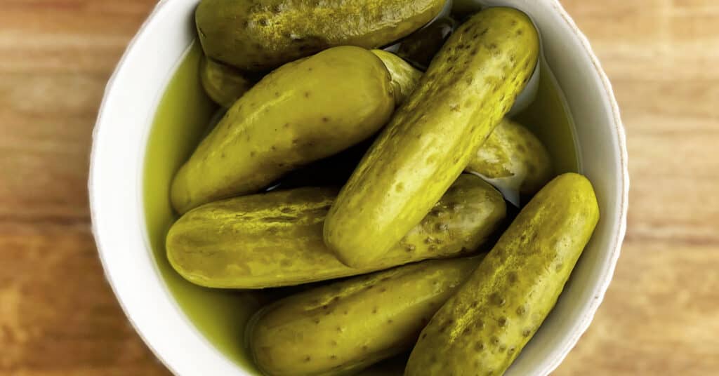 Dill Pickles in a Bowl on a Wooden Cutting Board