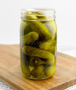 Dill Pickles in a Jar on a Wooden Cutting Board