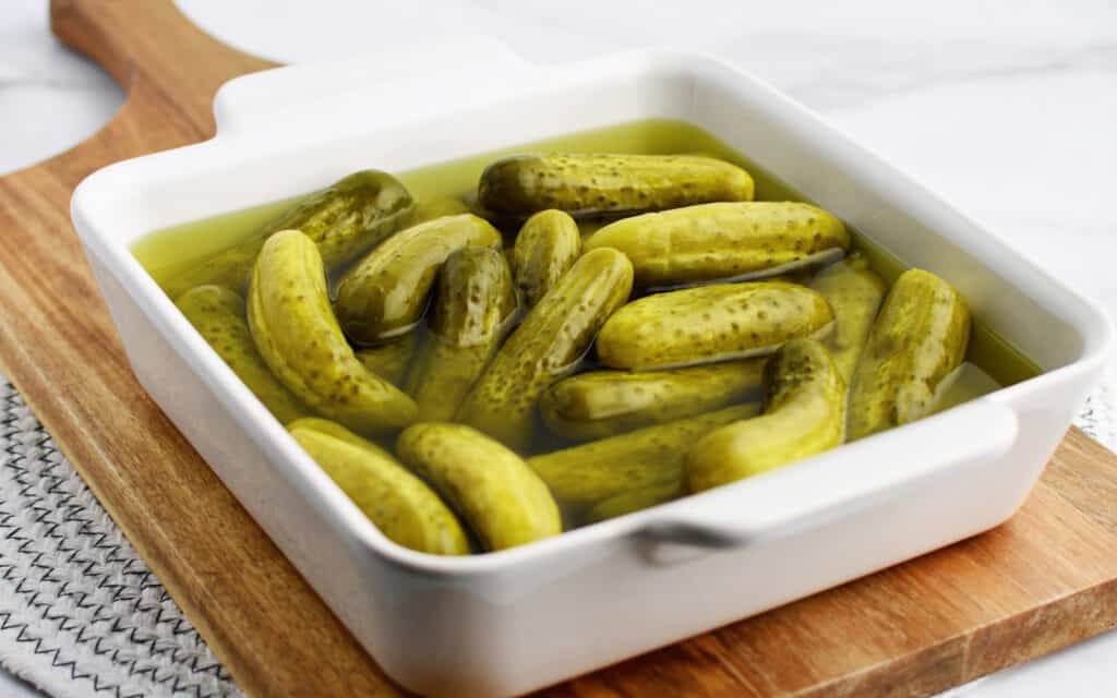 Baby Dill Pickles in White Dish on Wooden Surface