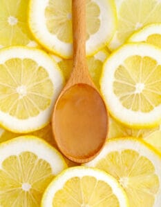 Wooden Tablespoon of Lemon Juice on Top of Lemon Slices