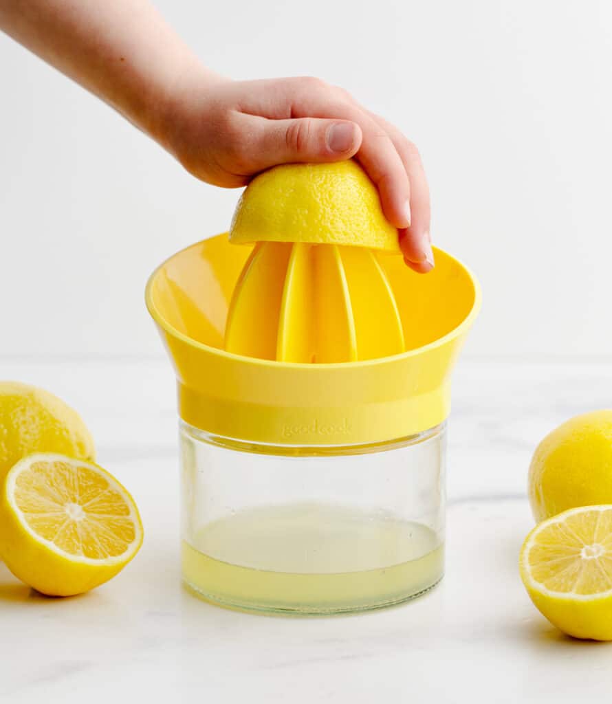 Juicing Lemon Using Hand Citrus Reamer with Lemons on a Marble Surface